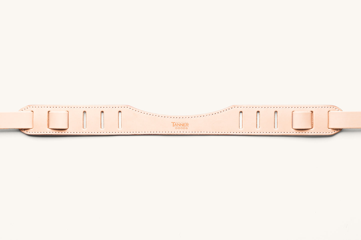 A natural SLR strap focusing on the shoulder piece with "Tanner Goods" stamped into the leather.