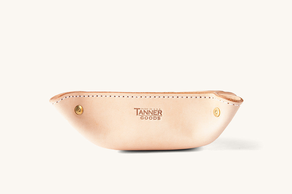 Natural leather valet tray by Tanner Goods, boat-shaped with white stitching and brass snaps.