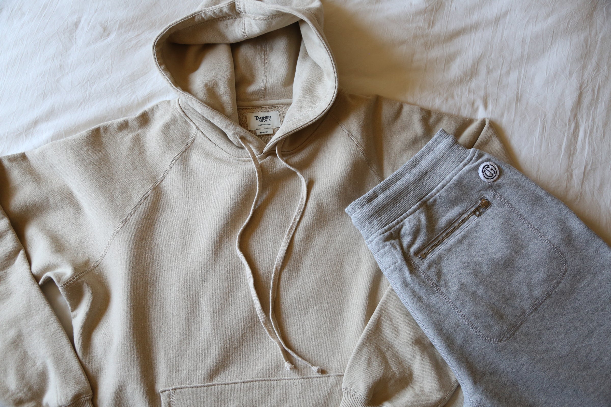Soft beige hoodie and gray sweatpants with zipper pocket, minimalist comfort for relaxed woodland style.