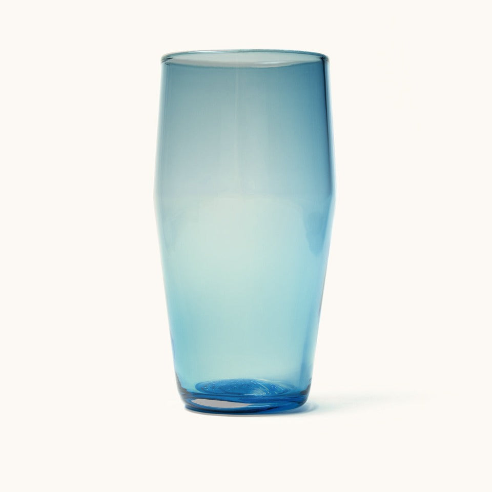A translucent blue pint glass with a tapered shape, casting a soft shadow on a white background.