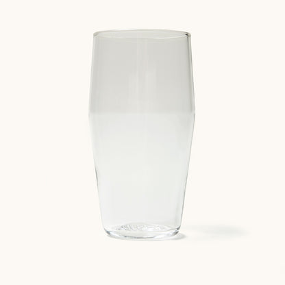 A clear glass pint glass with a slightly tapered shape and textured base, casting a subtle shadow.