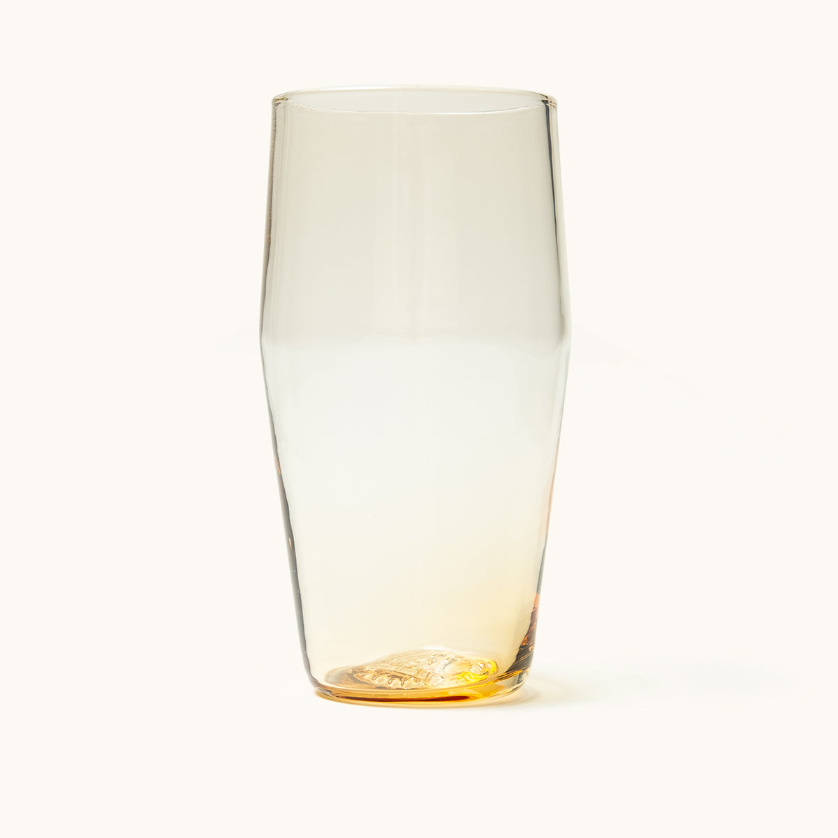 Tapered pint glass with a clear body and a golden amber base featuring textured indentations.
