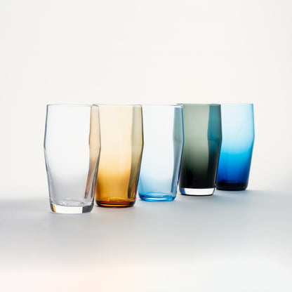 Five standard pint glasses in clear, amber, light blue, grey-green, and cobalt, arranged diagonally on a white surface.