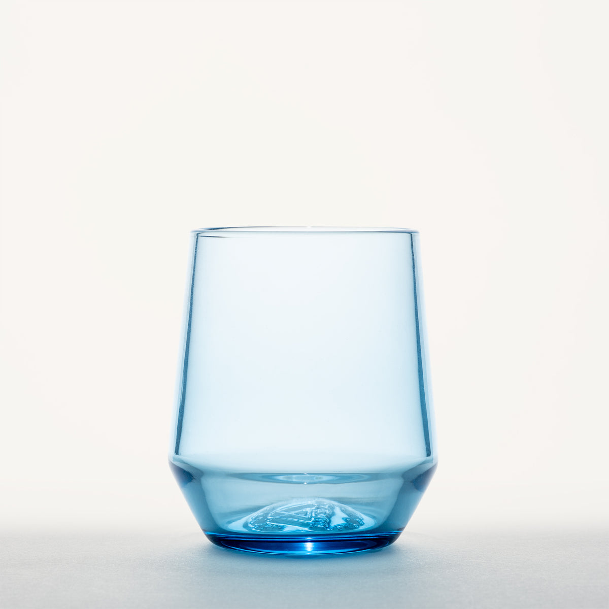 Stemless light blue wine glass with a thick, faceted base and embossed logo, shown front-on against a white background.