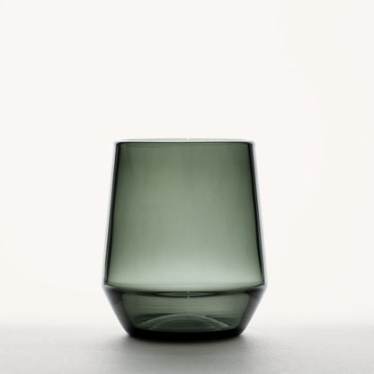 Smoke green stemless wine glass with a thick base and tapered sides against a white background
