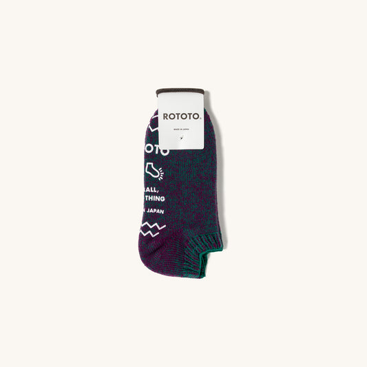 Purple and green pile sock slipper by Rototo with white text and zigzag knit pattern.