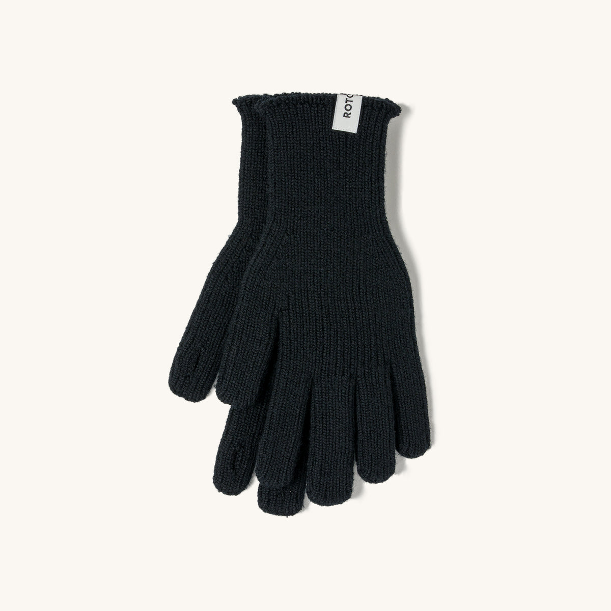 Black merino knit touch gloves with ribbed cuffs and a white brand tag, laid flat on a cream background.