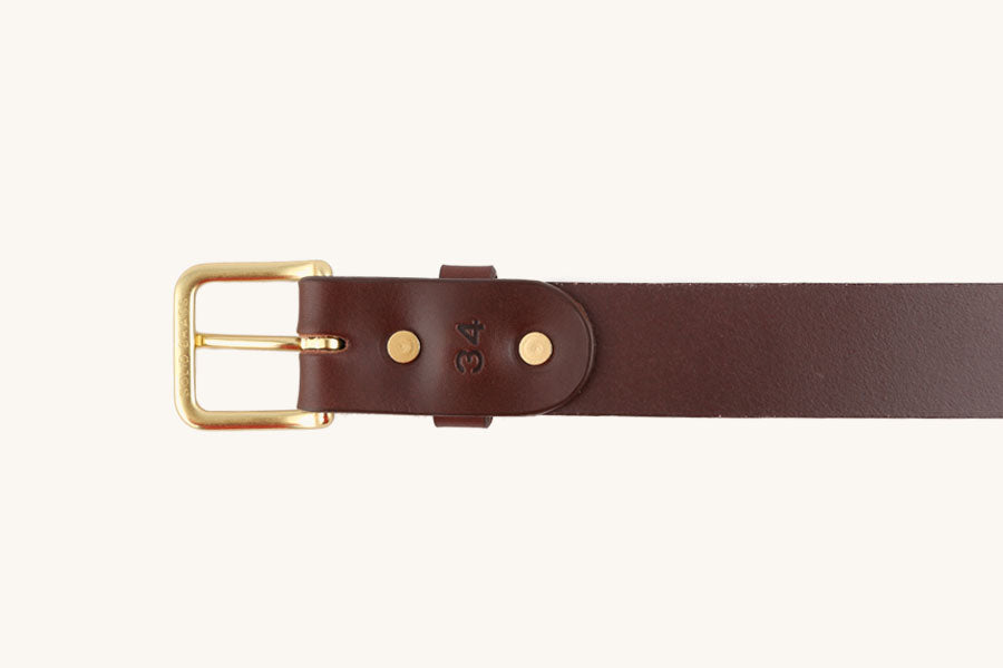 Cognac leather belt with a gold-toned "SOLID BRASS" buckle and "34" stamped on the strap.