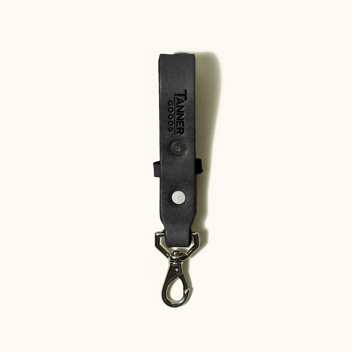 Black leather Key Lanyard by Tanner Goods, embossed with logo, featuring two silver rivets and a metal carabiner clip.
