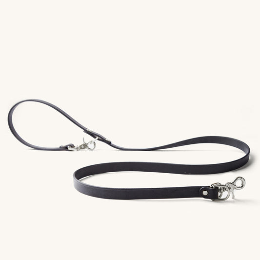 Black convertible canine lead with silver-tone snap hooks, made of a flat strap, displayed on white.