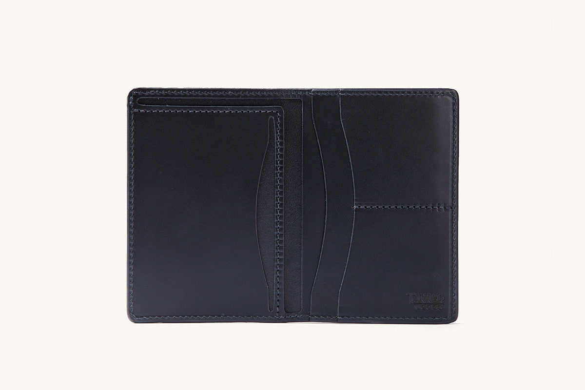 Smooth black travel wallet, open flat, revealing multiple card slots, slip pockets, and a debossed logo.